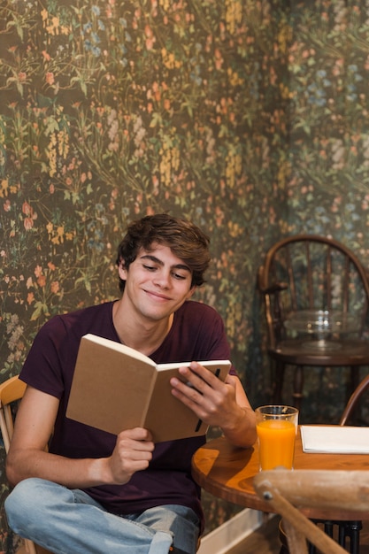 Adolescente alegre lendo no café