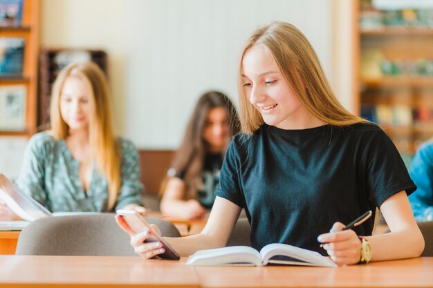 Adolescente alegre usando smartphone na aula