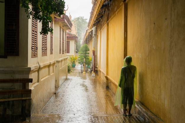 Adolescente asiático esperando a chuva de monção parar.