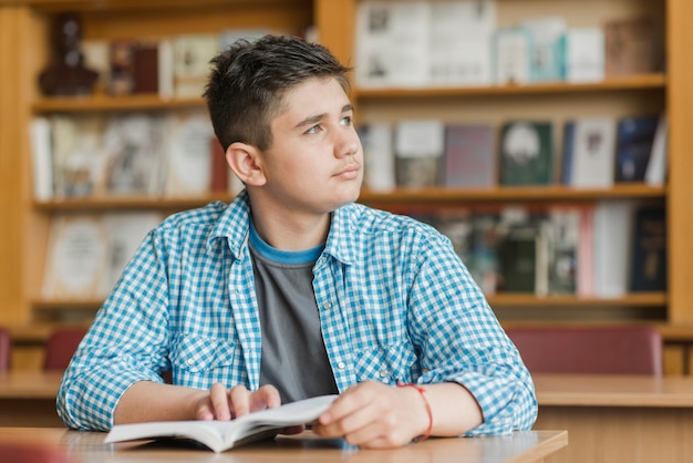 Adolescente com livro a desviar o olhar