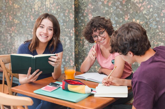 Adolescente com livro perto de estudar amigos