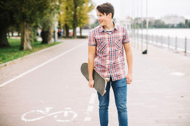 Adolescente com skateboard perto da pista de bicicleta