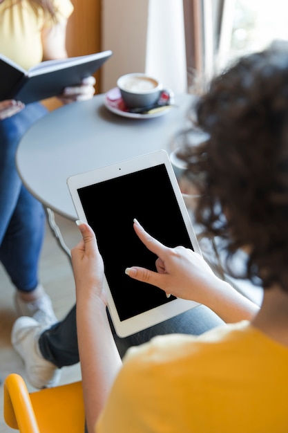 Adolescente de colheita usando o tablet na mesa