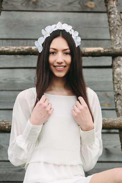 Adolescente de sorriso com uma coroa de flores consideravelmente floral