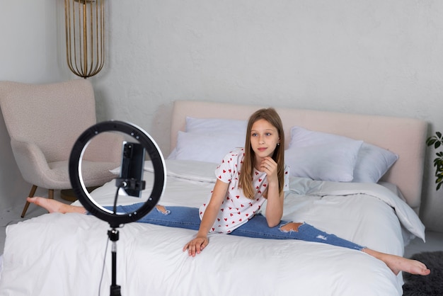 Foto grátis adolescente de tiro completo fazendo as divisões na cama