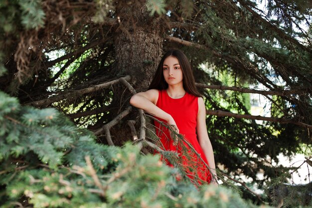 Adolescente de vestido vermelho posou ao ar livre em dia ensolarado