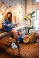 Foto grátis adolescente e menina gravando música em seu estúdio caseiro com guitarra