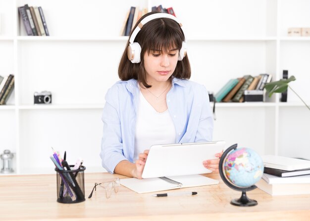 Adolescente, estudante, em, fones, sentando tabela, com, tabuleta, em, mãos