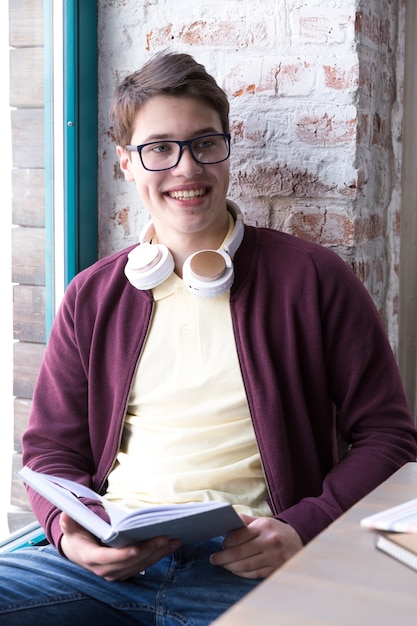 Foto grátis adolescente, estudante, em, óculos, e, sentando mesa, e, livro leitura