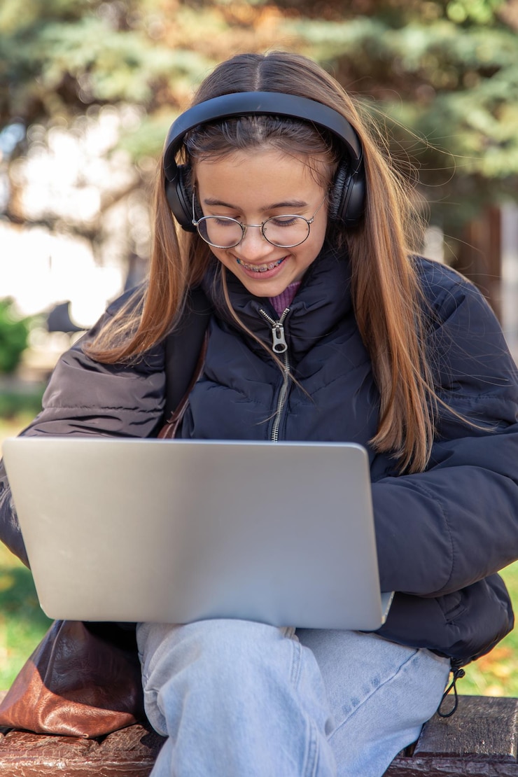 Foto grátis adolescente feliz com fones de ouvido trabalha em um conceito de emoções de laptop