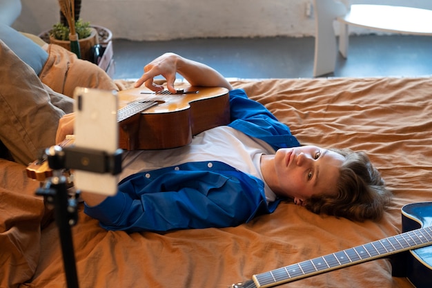 Foto grátis adolescente gravando música com sua guitarra em seu estúdio em casa