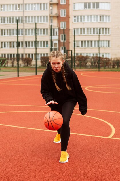 Adolescente jogando basquete ao ar livre