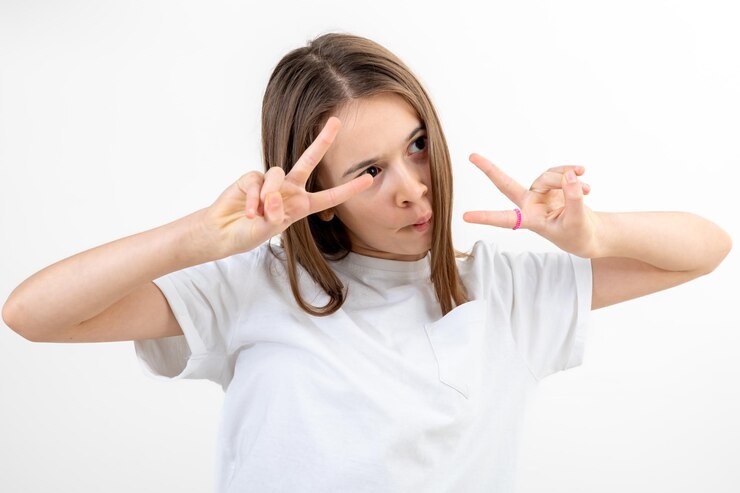 Foto grátis adolescente morena com uma camiseta branca faz caretas em um fundo branco