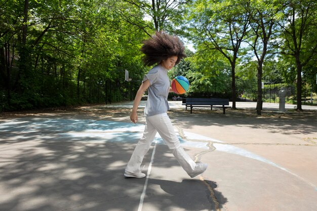 Adolescente negra sorridente jogando basquete