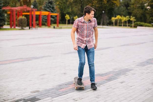 Adolescente no skate empurrando do pavimento