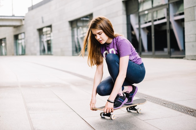 Adolescente que ajusta o skateboard