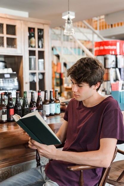 Adolescente relaxado lendo perto balcão de café