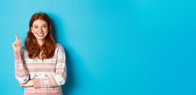 Adolescente ruiva excitada tendo uma ideia levantando o dedo e sorrindo sugerindo algo em pé