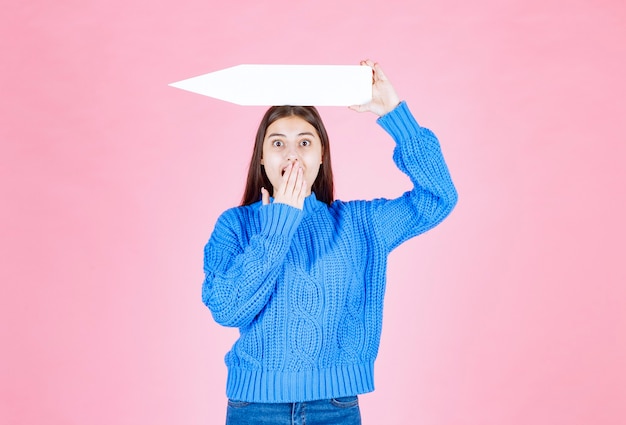 Adolescente segurando uma flecha de papel como um ponteiro de lado.