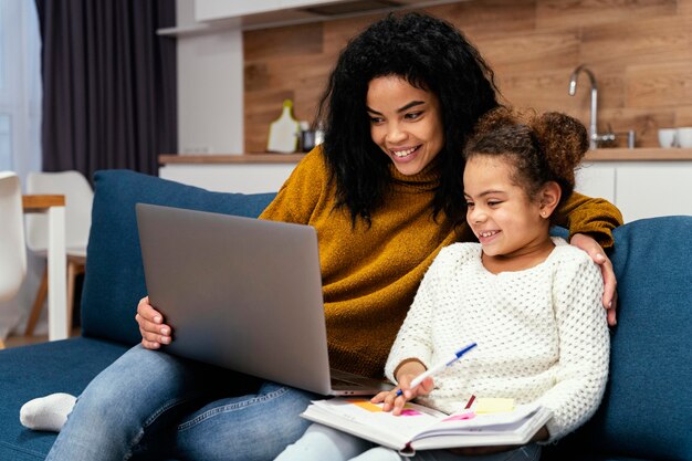 Adolescente sorridente ajudando a irmãzinha na escola online