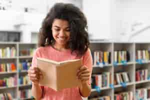 Foto grátis adolescente sorridente na biblioteca de leitura