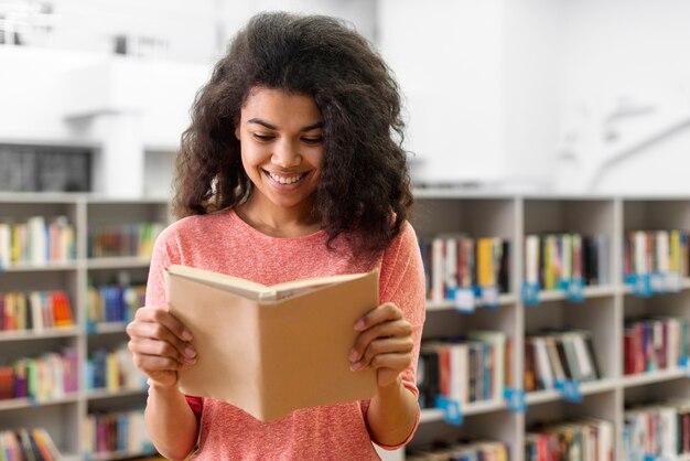 Adolescente sorridente na biblioteca de leitura