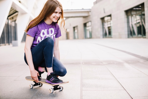 Adolescente sorridente que aprende a andar de skate