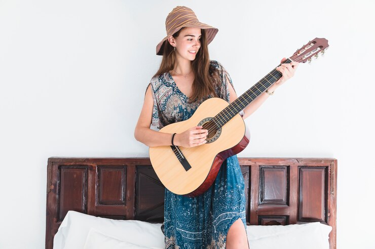 Foto grátis adolescente talentoso em pé na cama tocando violão