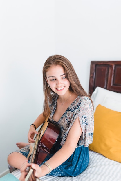 Foto grátis adolescente talentoso tocando violão no quarto