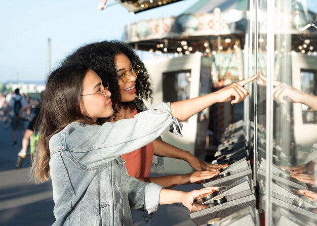 Adolescentes bonitos que apreciam o parque de diversões