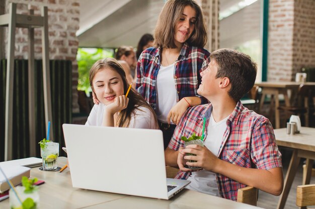 Adolescentes com laptop gastando tempo no café