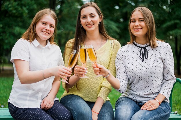 Adolescentes com taças de champanhe, olhando para a câmera