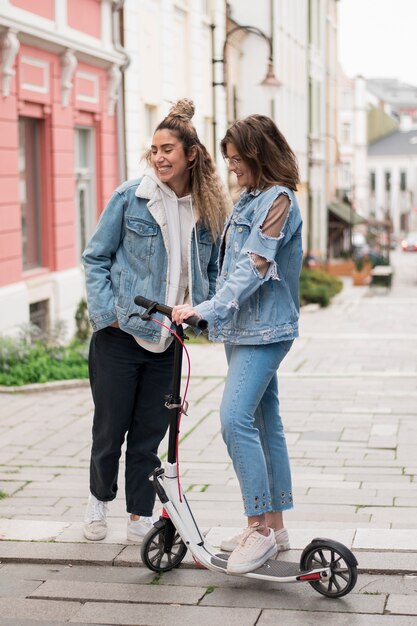 Adolescentes elegantes posando com scooter elétrica