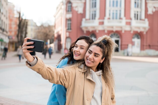 Adolescentes elegantes tomando uma selfie ao ar livre