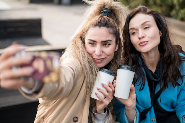 Adolescentes elegantes tomando uma selfie ao ar livre