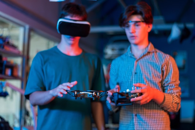 Adolescentes fazendo experimentos em robótica em um laboratório Garoto com óculos de proteção e cara com fone de ouvido VR