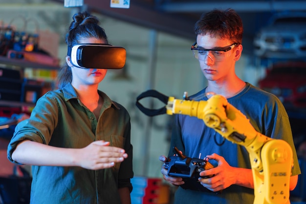 Adolescentes fazendo experimentos em robótica em um laboratório Garoto com óculos de proteção e garota com fone de ouvido VR