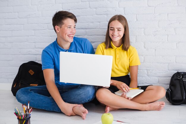 Adolescentes rindo e usando laptop