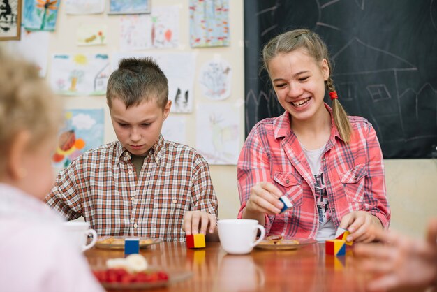 Adolescentes sentados a mesa brincando sorrindo