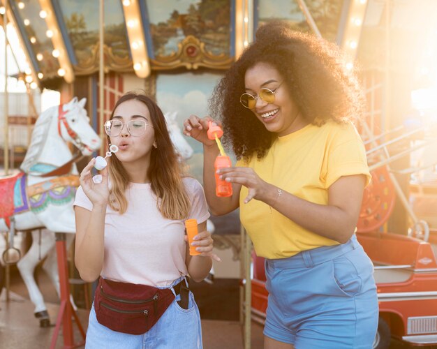 Adolescentes soprando bolhas no parque de diversões