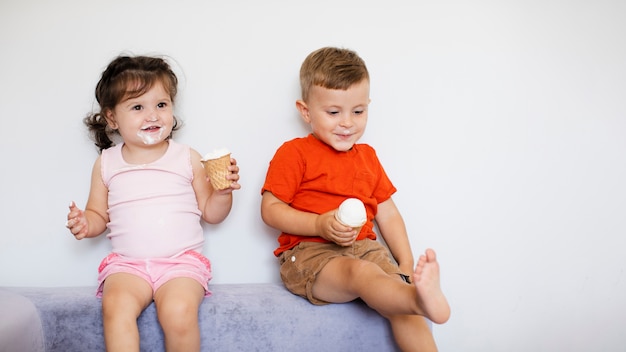 Adoráveis crianças sentadas e desfrutando de seus sorvetes