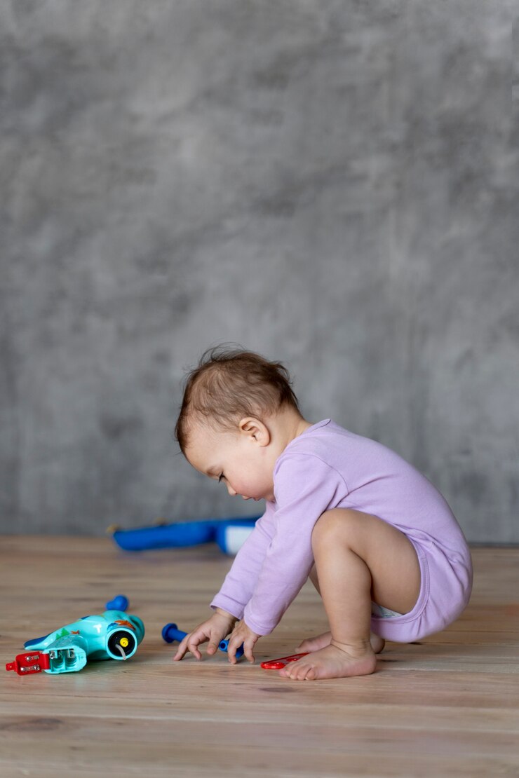 Foto grátis adorável bebê brincando no chão com brinquedo