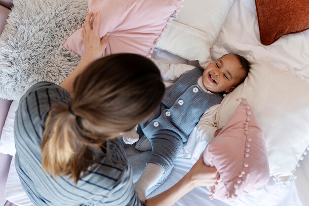 Adorável bebê rindo e brincando com sua mãe na cama