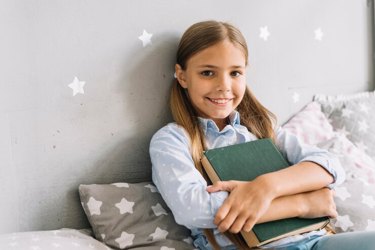 Foto grátis adorável garota feliz posando com um livro