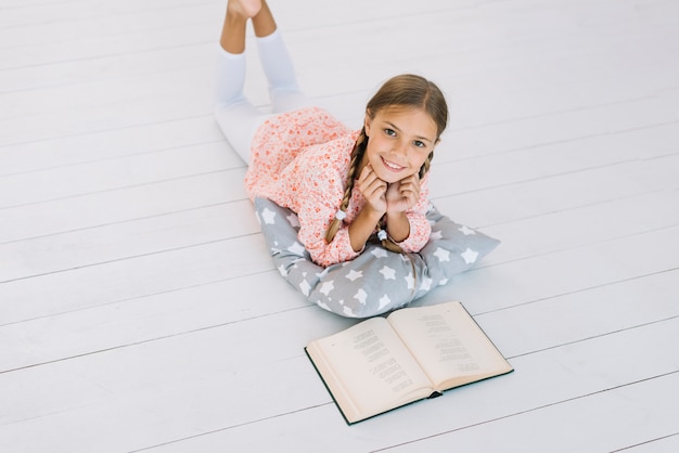 Adorável garota feliz posando com um livro