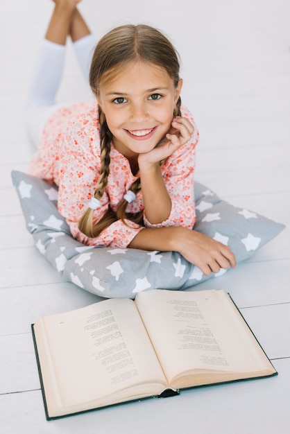 Adorável garota feliz posando com um livro