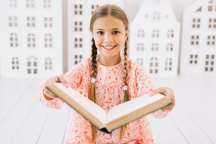 Foto grátis adorável garota feliz posando com um livro