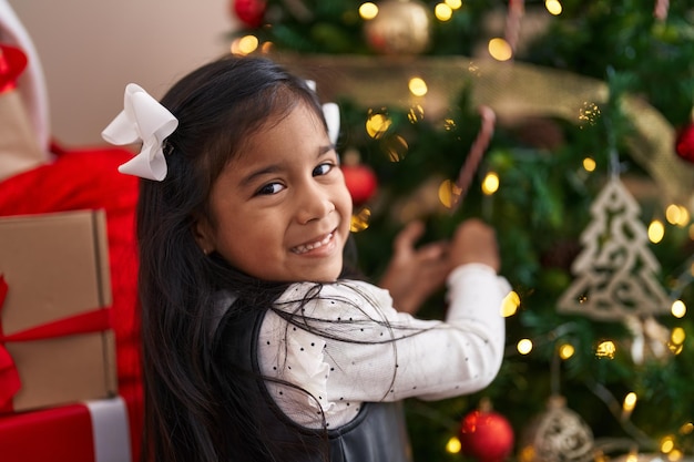 Foto grátis adorável garota hispânica sorrindo confiante decorando a árvore de natal em casa