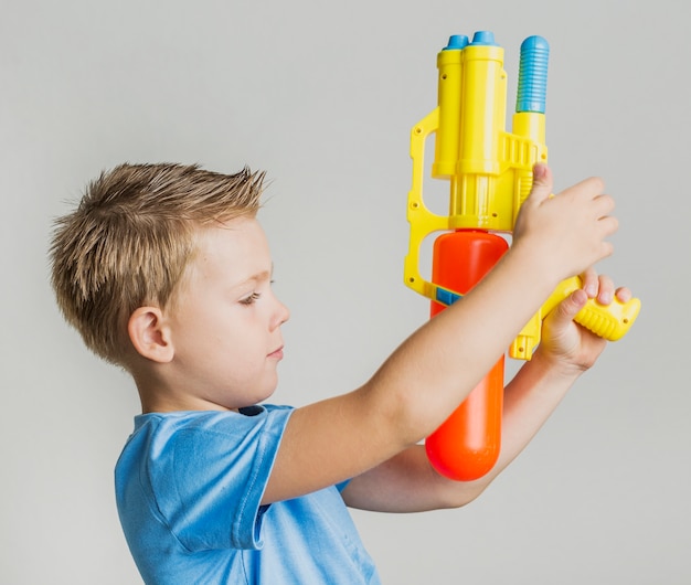 Foto grátis adorável garoto brincando com pistola de água