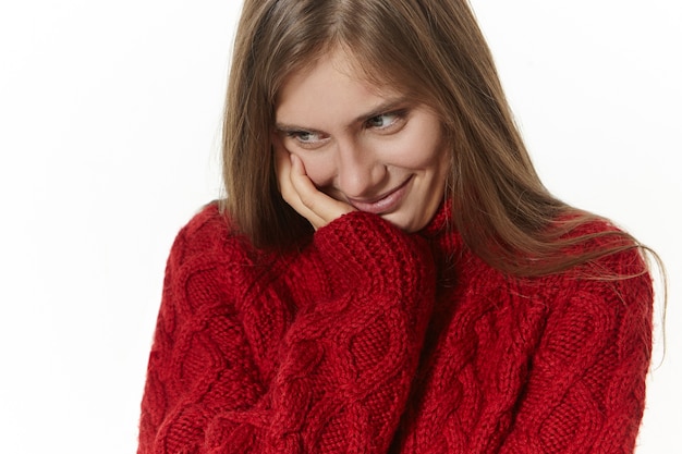 adorável jovem atraente com cabelos brilhantes soltos olhando para baixo com um sorriso tímido e tímido, sentindo-se envergonhada em uma situação estranha